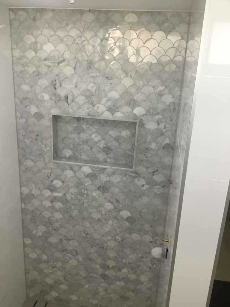 Shower tiled with Carrara marble fan shaped mosaic